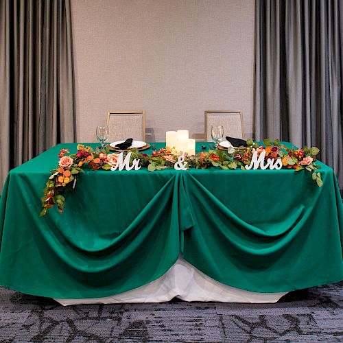 A decorative table setup with a green tablecloth, flower arrangements, and 