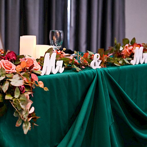 A decorated table with a green tablecloth, flowers, candles, and 