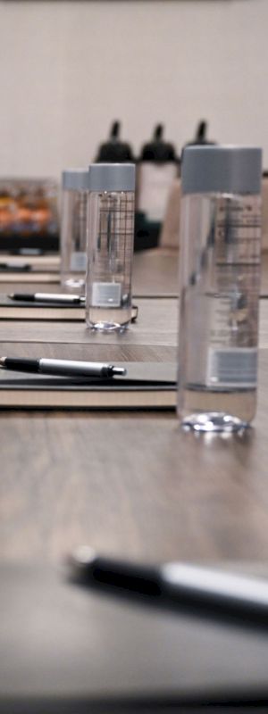 A conference table is set up with notebooks, pens, and water bottles, ready for a meeting.