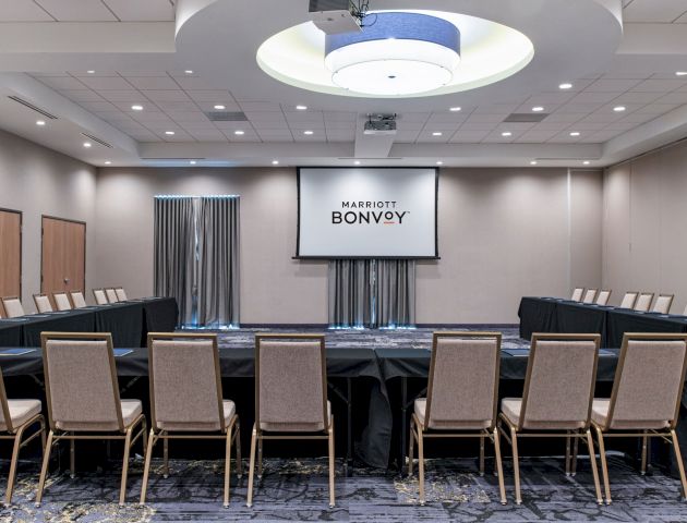 This image shows a conference room setup with chairs arranged in a U-shape, a projector screen displaying 