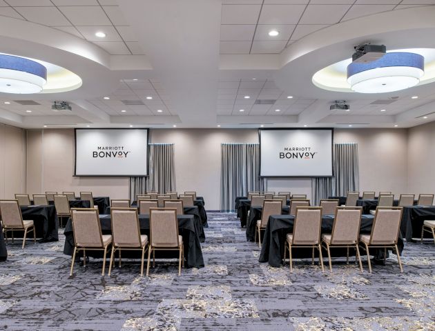 A conference room is set up with chairs facing two projection screens displaying 
