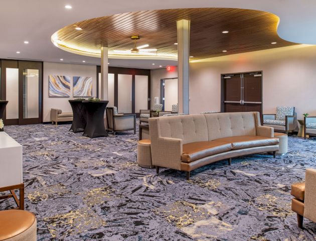 This image shows a modern, spacious lobby with contemporary furniture, patterned carpet, and decorative lighting, creating a welcoming atmosphere.